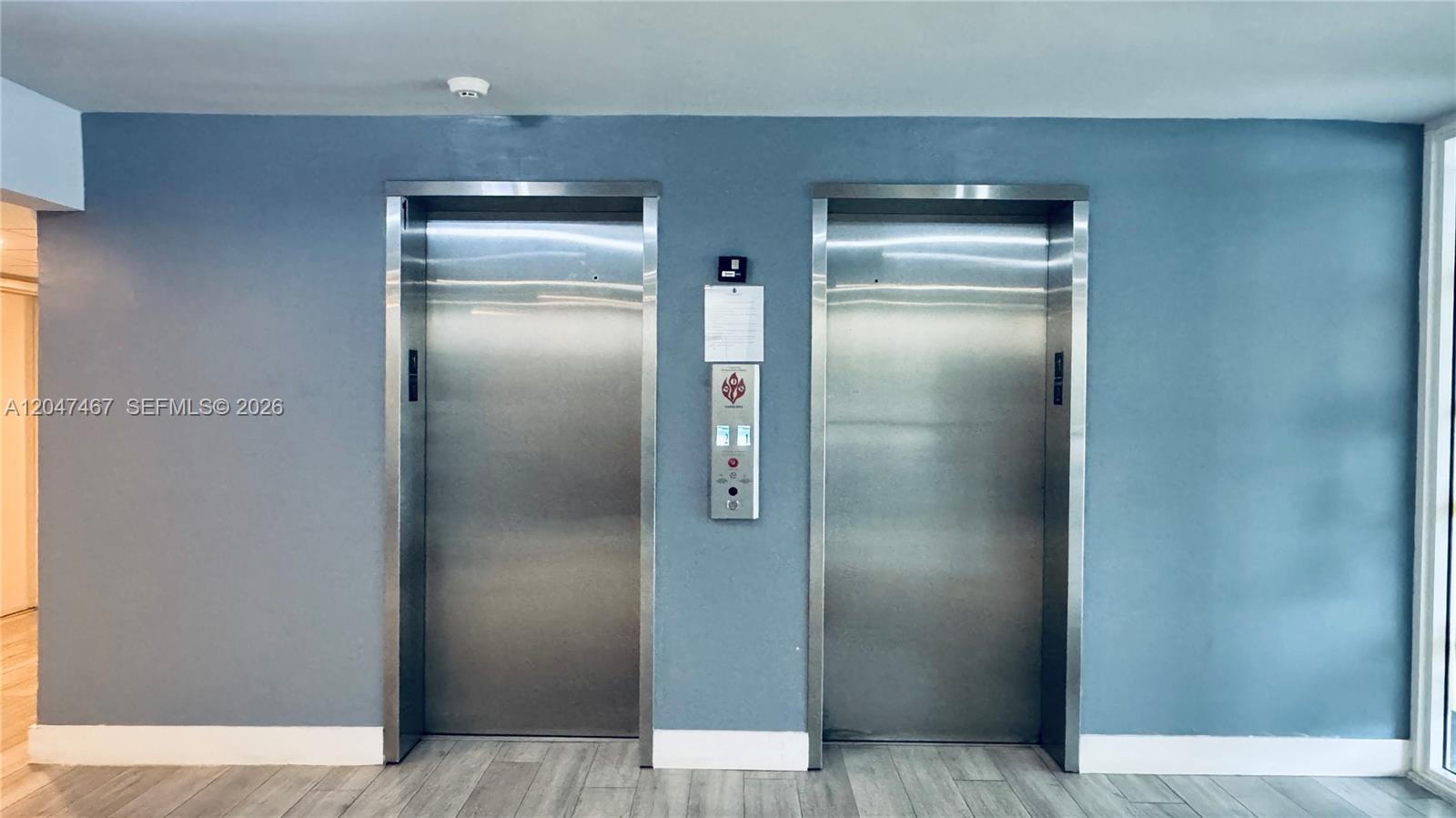 Two stainless steel elevator doors are set into a blue wall above wood-look flooring — 9125 SW 77th Ave # 501, Miami FL 33156, MIAMI, FL