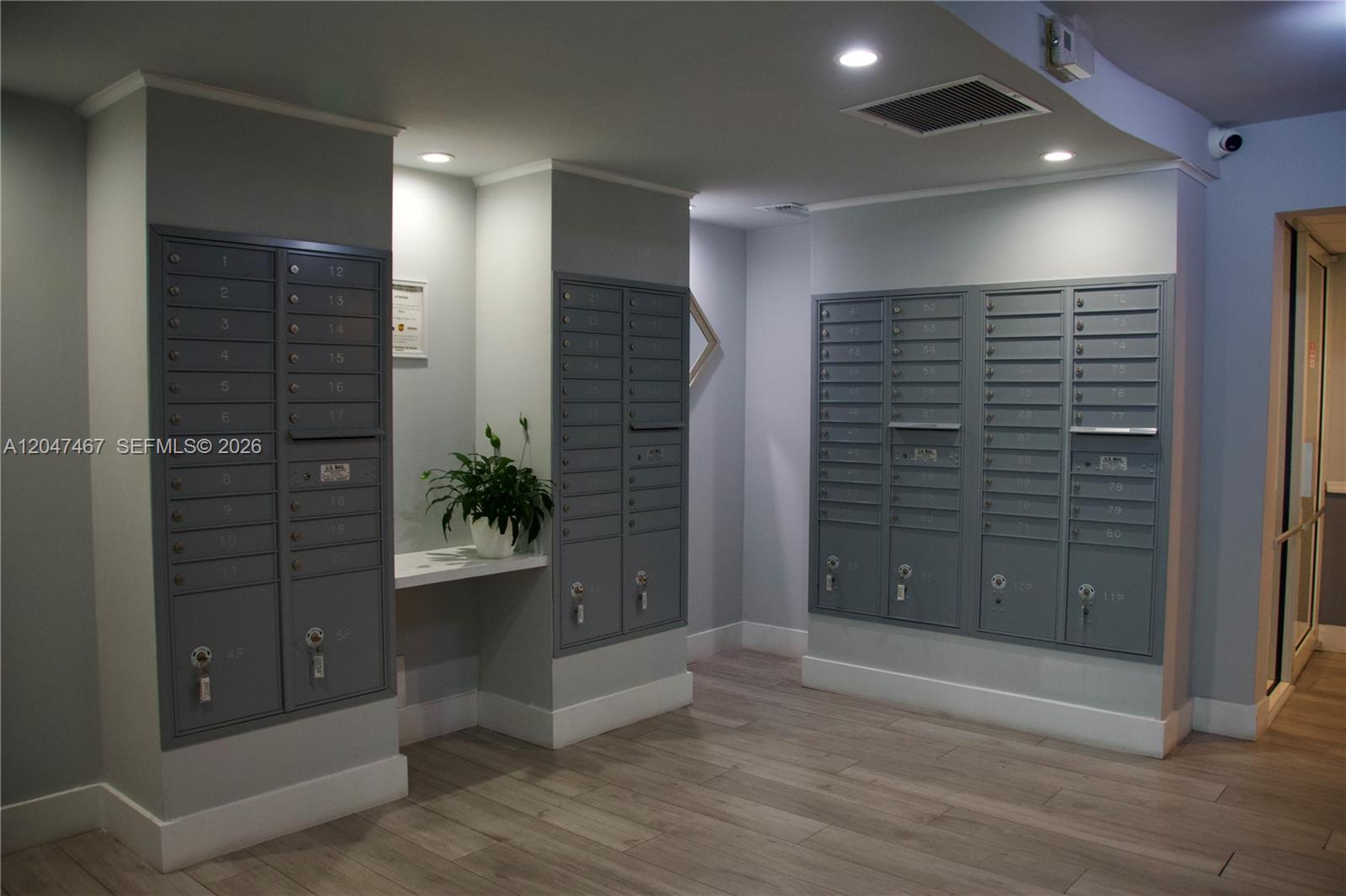 A mailroom features rows of gray metal mailboxes, light wood-look flooring, and recessed ceiling lights — 9125 SW 77th Ave # 501, Miami FL 33156, MIAMI, FL