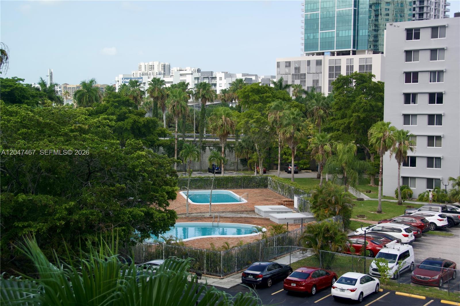 An elevated view of two swimming pools, a parking lot, and surrounding apartment buildings — 9125 SW 77th Ave # 501, Miami FL 33156, MIAMI, FL