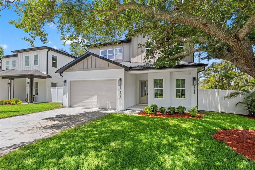 A two-story house with a white stucco facade, a gray garage door, and a large tree — 10198 HODSON PLACE, SEMINOLE, FL