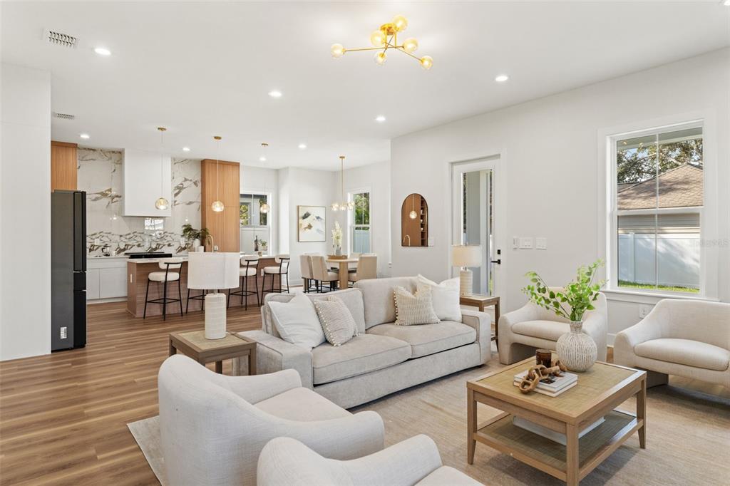 An open-concept living room and kitchen featuring light wood floors, neutral furniture, and marble accents — 10198 HODSON PLACE, SEMINOLE, FL