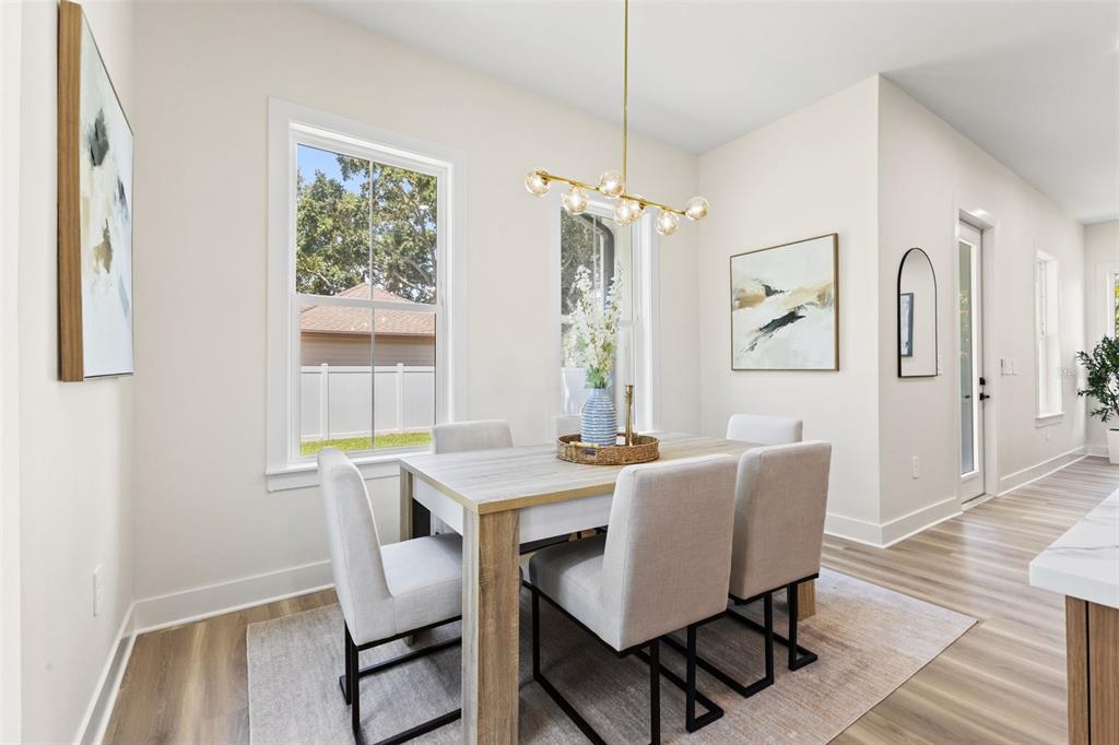 A dining area features a light wood table, upholstered chairs, and a modern gold chandelier — 10198 HODSON PLACE, SEMINOLE, FL