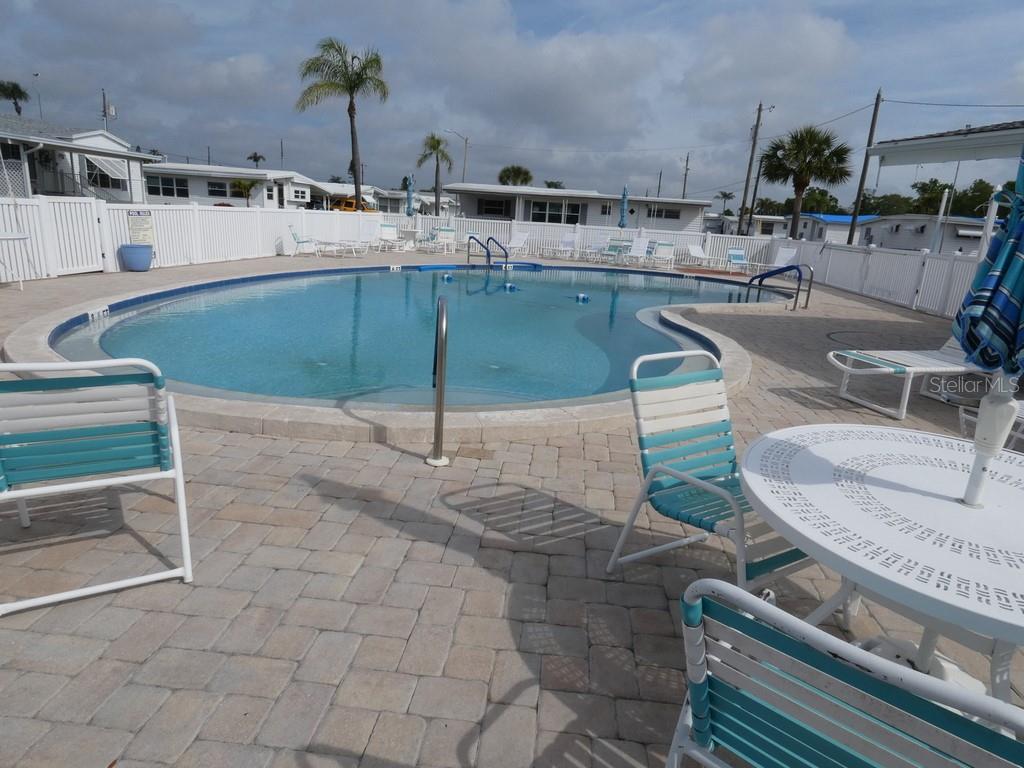 A swimming pool is surrounded by a paved patio with outdoor chairs and tables — 2900 GULF TO BAY BOULEVARD UNIT 234, CLEARWATER, FL