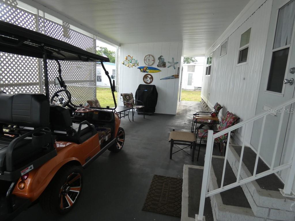 A covered patio area features a golf cart, outdoor seating, and decorative wall art — 2900 GULF TO BAY BOULEVARD UNIT 234, CLEARWATER, FL