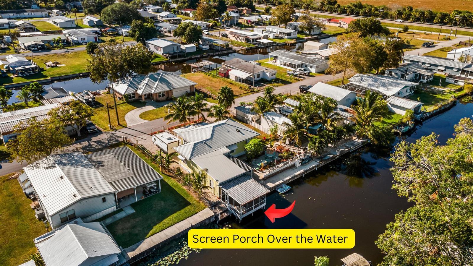 An aerial view shows a house with a screened porch extending over a canal — 1099 7th Street, Okeechobee FL 34974, OKEECHOBEE, FL