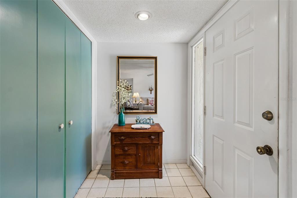 An entryway features a teal closet, a wooden chest, a mirror, and a white door — 6067 FAIRWAY LANE UNIT 1413, BRADENTON, FL
