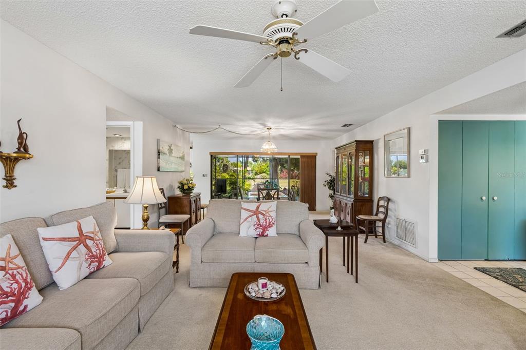 A living room features beige sofas, a wooden coffee table, and a ceiling fan — 6067 FAIRWAY LANE UNIT 1413, BRADENTON, FL