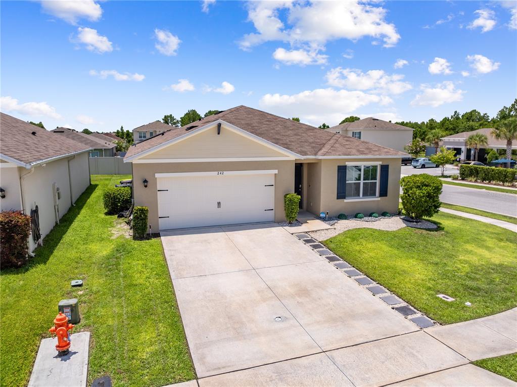 An exterior view of a single-story suburban house with a two-car garage and driveway — 1242 IGUANA LOOP, DAVENPORT, FL
