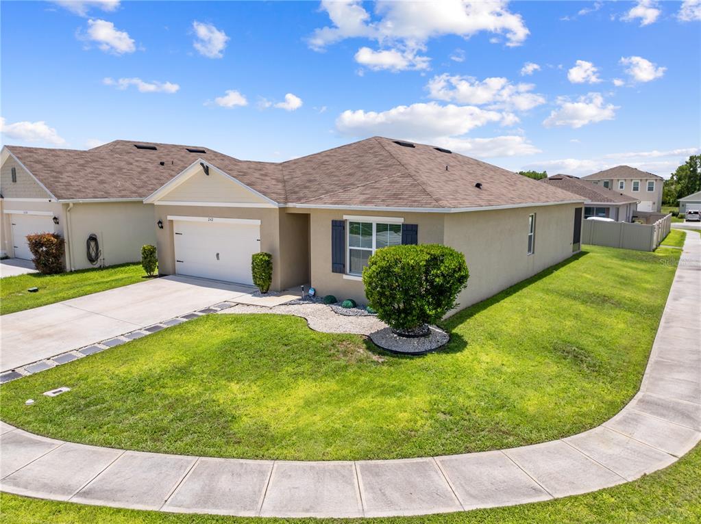 A single-story suburban house with a tan stucco exterior, brown roof, and a two-car garage — 1242 IGUANA LOOP, DAVENPORT, FL