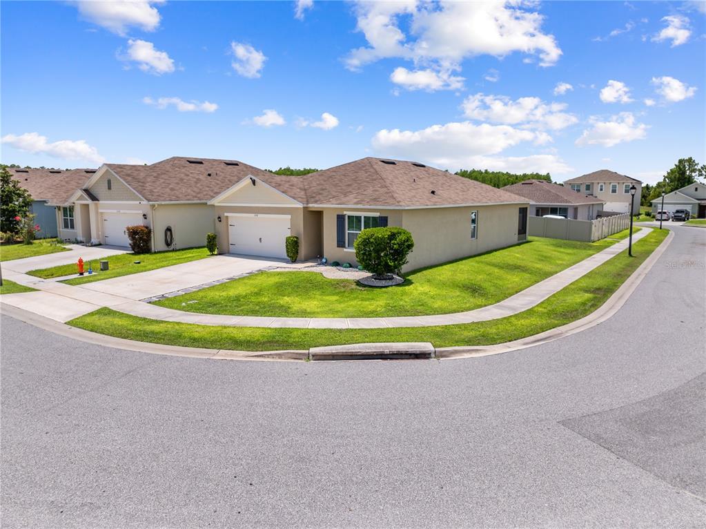 A corner lot features a single-story suburban house with a tan exterior and a driveway — 1242 IGUANA LOOP, DAVENPORT, FL