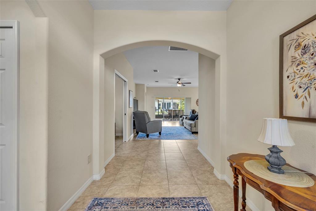 A tiled entryway leads through an arched doorway into a living room with a ceiling fan — 26669 OTTER CREEK LANE, LEESBURG, FL