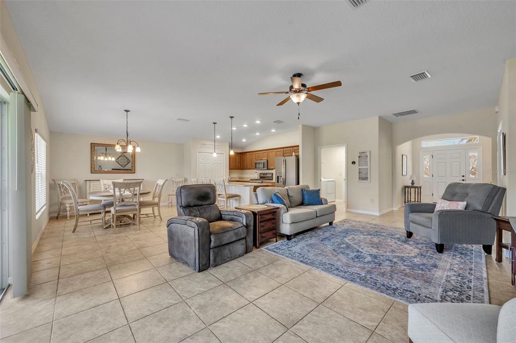 An open-concept living and dining area features tile flooring, a kitchen island, and neutral walls — 26669 OTTER CREEK LANE, LEESBURG, FL