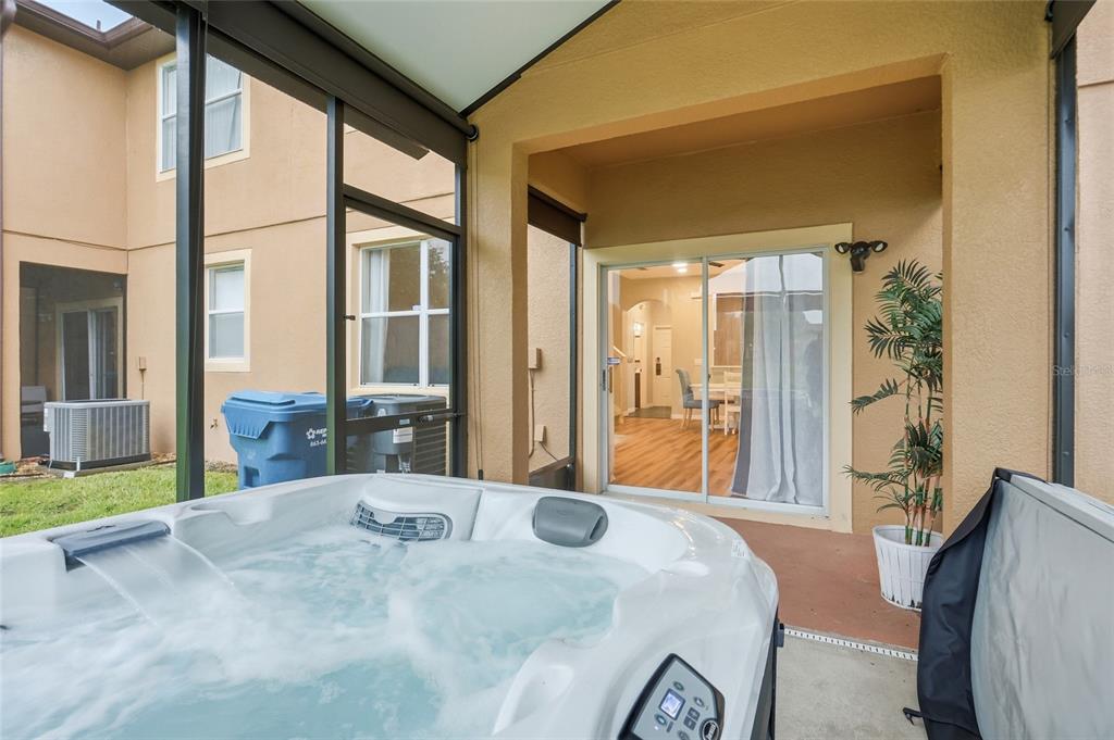 A hot tub sits on a screened-in patio next to a sliding glass door — 122 CAPRI DRIVE, DAVENPORT, FL