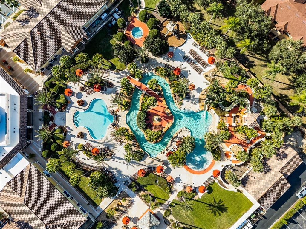 An aerial view shows a resort-style swimming pool complex with a lazy river and slides — 122 CAPRI DRIVE, DAVENPORT, FL