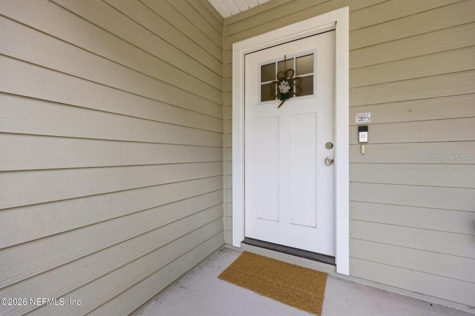 A white front door with a small window is set into light-colored horizontal siding — 4405 SUSAN STREET, HASTINGS, FL