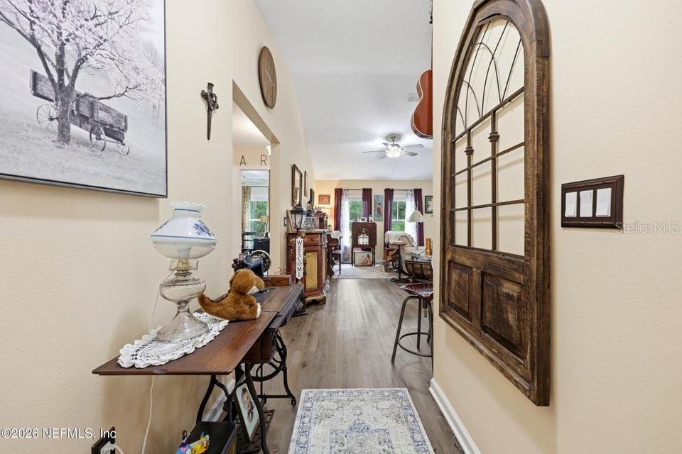 A hallway leads into a living area featuring wood-look flooring and a decorative arched mirror — 4405 SUSAN STREET, HASTINGS, FL