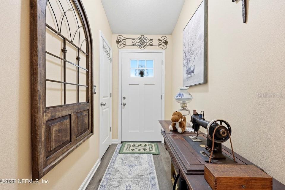 An entryway features a white door, a vintage sewing machine table, and wall decor — 4405 SUSAN STREET, HASTINGS, FL