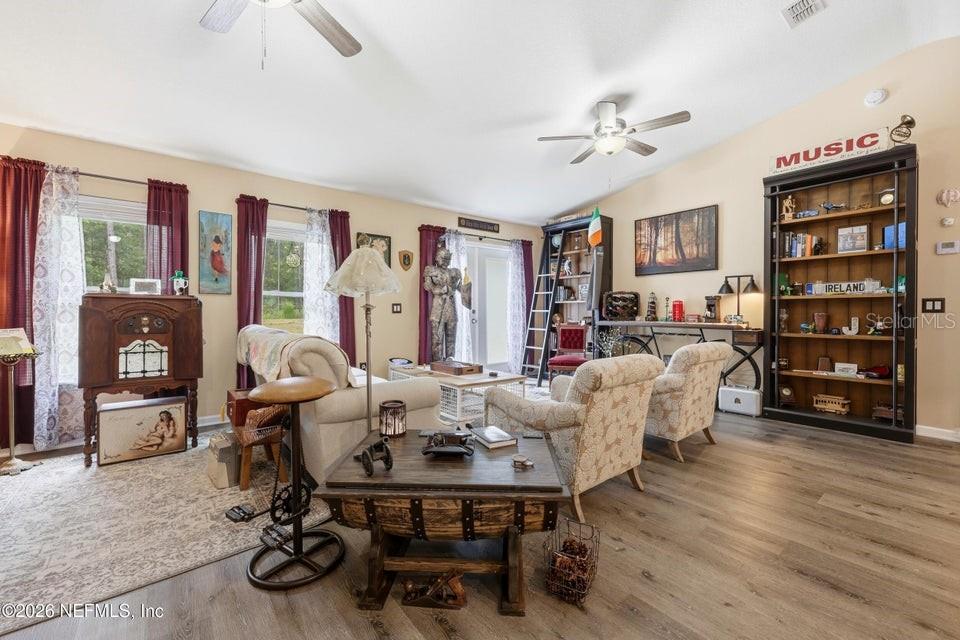 A living room features wood-look flooring, a ceiling fan, a bookshelf, and traditional furniture — 4405 SUSAN STREET, HASTINGS, FL