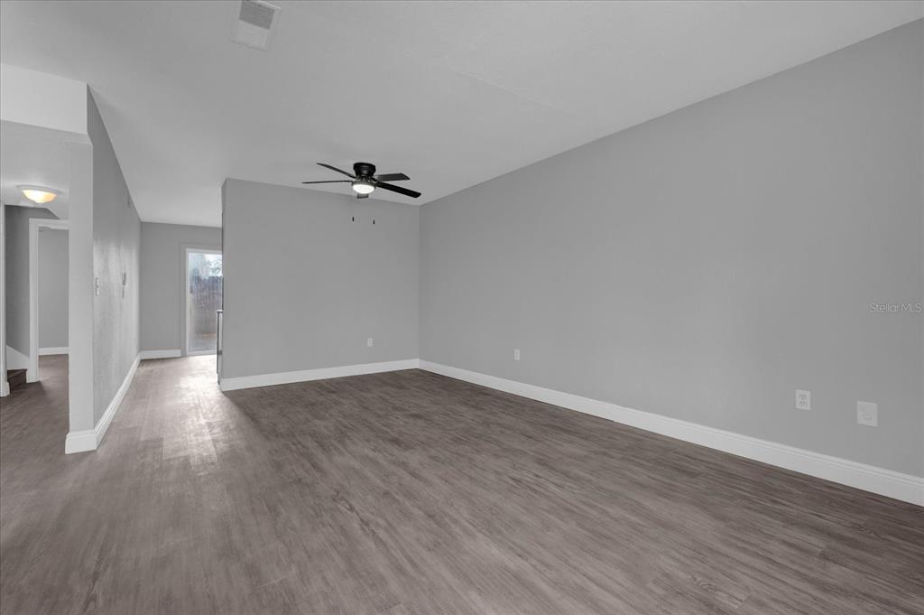 An empty room features gray walls, wood-look flooring, a ceiling fan, and white baseboards — 2418 SKAN COURT UNIT C, ORLANDO, FL
