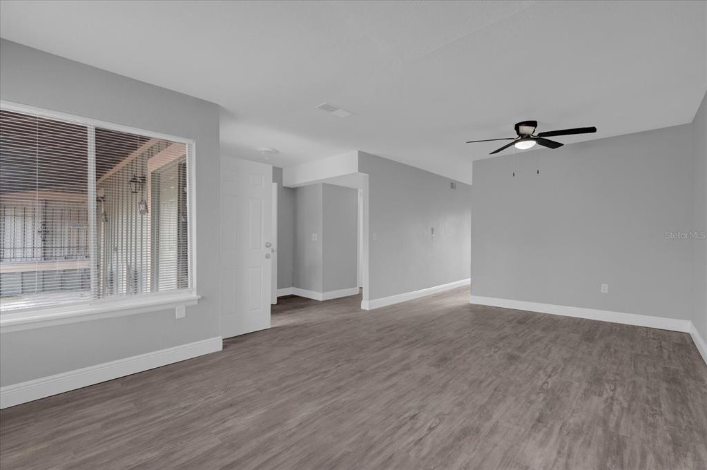 An empty room features gray walls, wood-look flooring, a ceiling fan, and a large window — 2418 SKAN COURT UNIT C, ORLANDO, FL