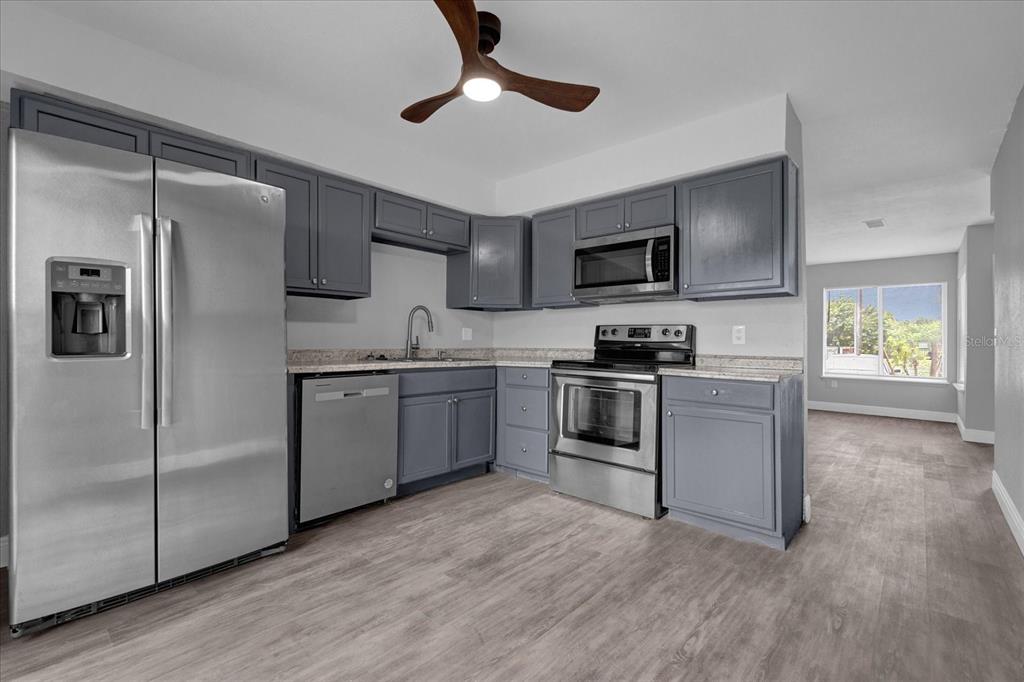 A kitchen with gray cabinets, stainless steel appliances, and light wood-look flooring — 2418 SKAN COURT UNIT C, ORLANDO, FL