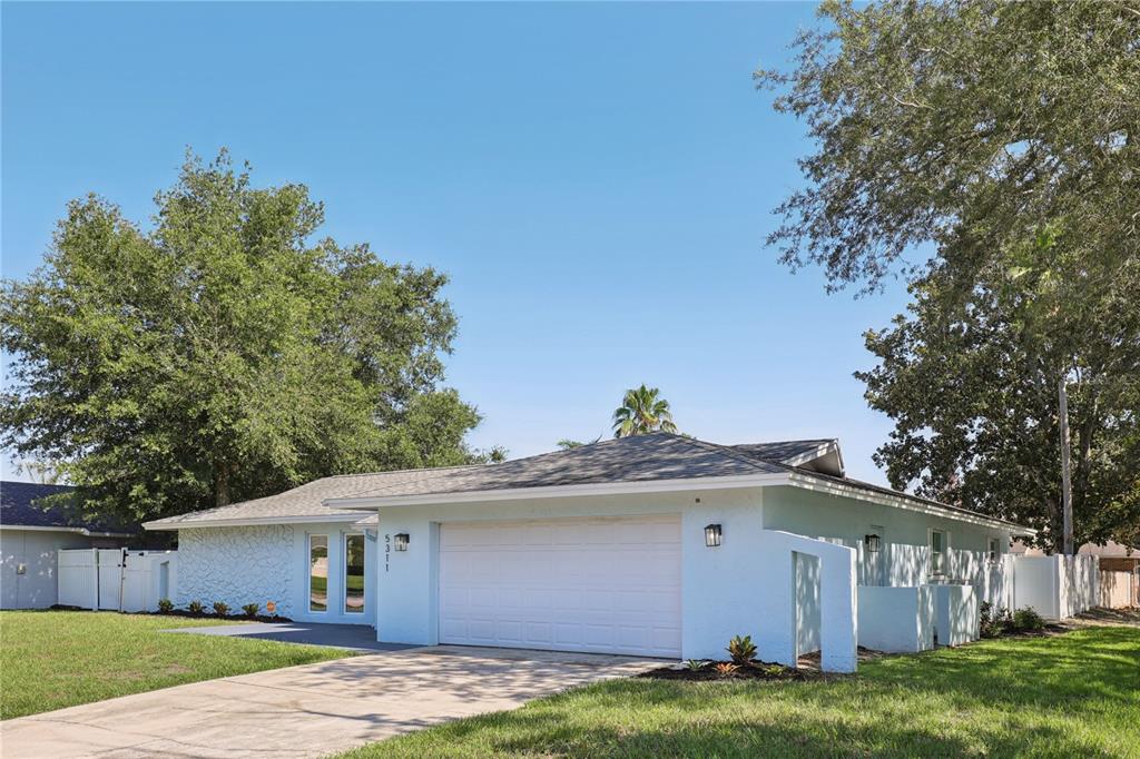 The exterior of a house features a light blue stucco wall, three tall windows, and a white front door — 5311 JENNIFER PLACE, ORLANDO, FL