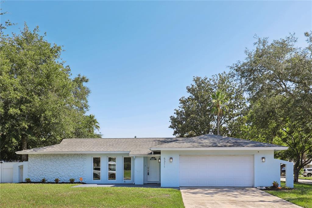 A single-story house with white stone siding, a gray shingled roof, and an attached garage — 5311 JENNIFER PLACE, ORLANDO, FL