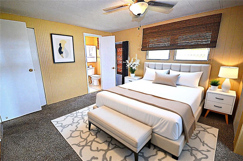 A bedroom features a bed with a bench, a ceiling fan, and an attached bathroom — 115 RACHEL DRIVE, TARPON SPRINGS, FL