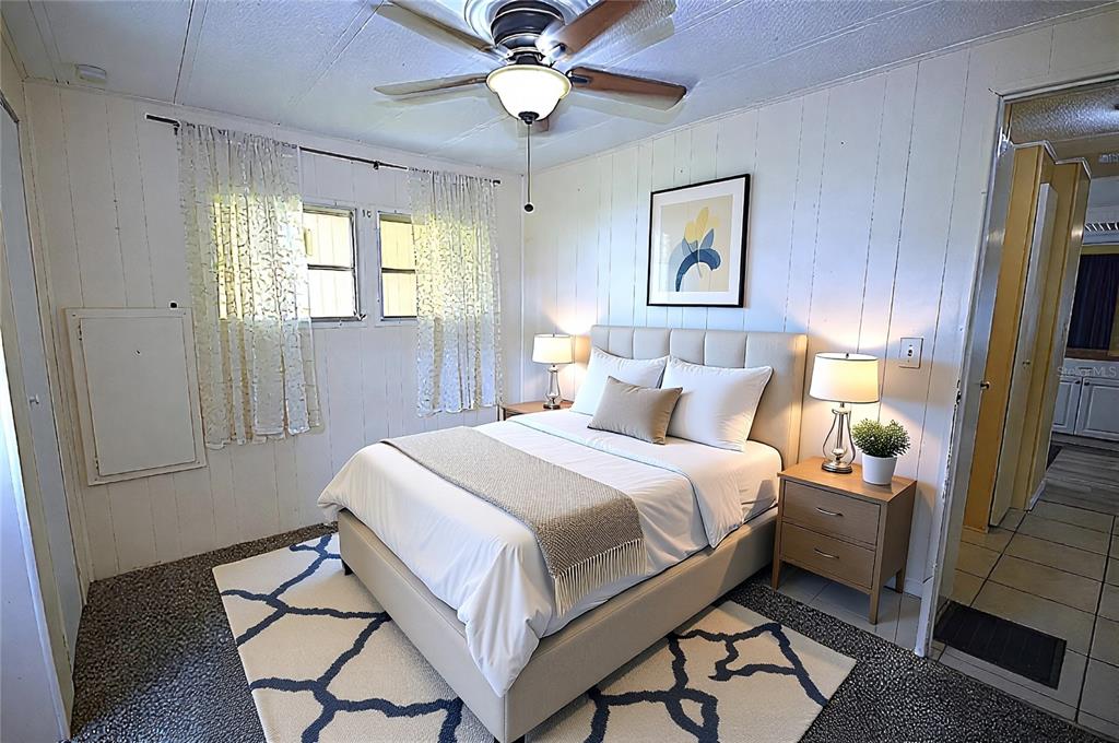A bedroom features a bed with a beige headboard, white walls, and a ceiling fan — 115 RACHEL DRIVE, TARPON SPRINGS, FL