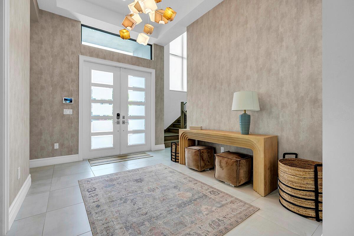 A modern entryway features a textured accent wall, a console table, and a patterned rug — 9046 Chauvet Way, Boca Raton FL 33496, BOCA RATON, FL