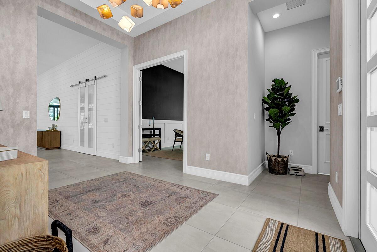 A bright entryway features tiled floors, a patterned rug, a potted plant, and modern lighting — 9046 Chauvet Way, Boca Raton FL 33496, BOCA RATON, FL