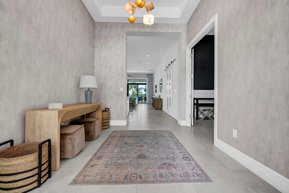 A modern entryway features a console table, area rug, and a view into the home — 9046 Chauvet Way, Boca Raton FL 33496, BOCA RATON, FL