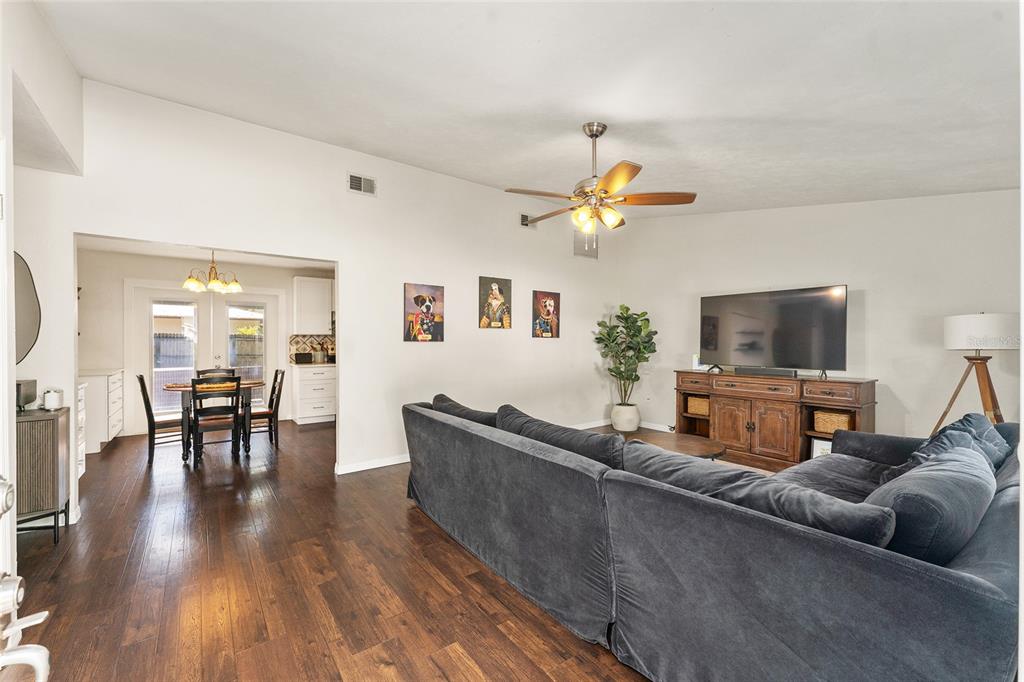 A living room with dark wood floors, a large sectional sofa, and a television console — 4321 NW 20TH STREET, GAINESVILLE, FL