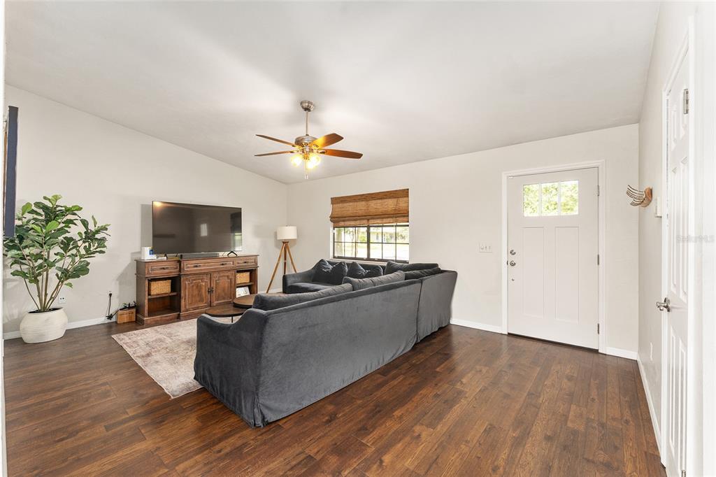 A living room features dark wood flooring, a gray sectional sofa, and a television console — 4321 NW 20TH STREET, GAINESVILLE, FL