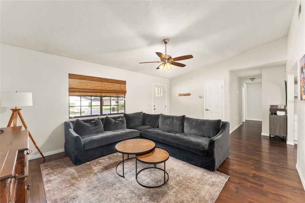 A living room features a dark gray sectional sofa, round nesting tables, and wood flooring — 4321 NW 20TH STREET, GAINESVILLE, FL