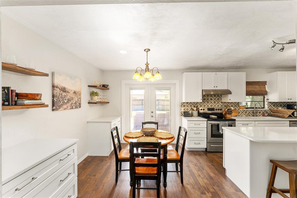 A kitchen and dining area with white cabinets, wood flooring, and a round wooden table — 4321 NW 20TH STREET, GAINESVILLE, FL