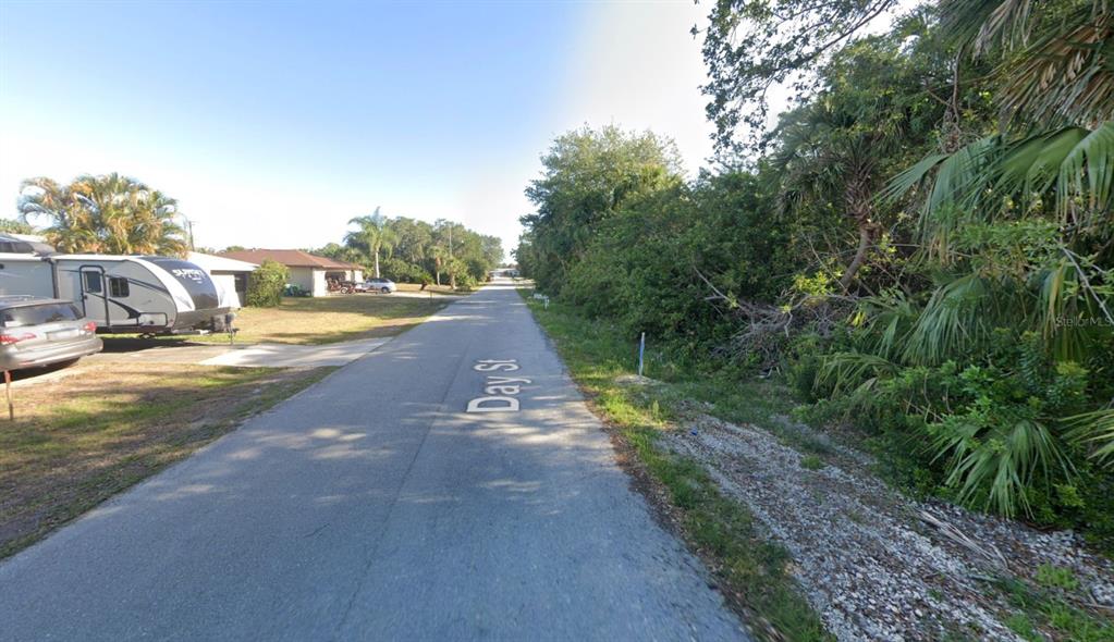 A paved street with a recreational vehicle parked on the left and dense vegetation nearby — 4250 DAY STREET, PORT CHARLOTTE, FL