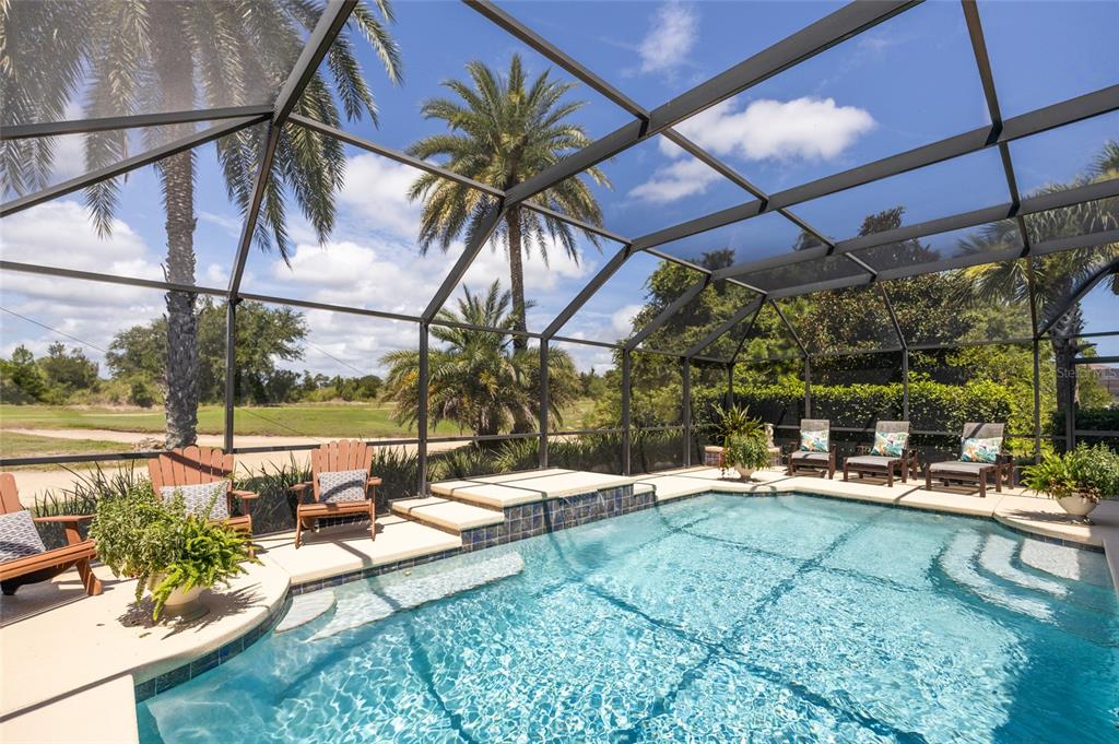 A screened-in swimming pool with a spillover spa, patio furniture, and palm trees outside — 478 SWEETGUM LANE, PALM COAST, FL