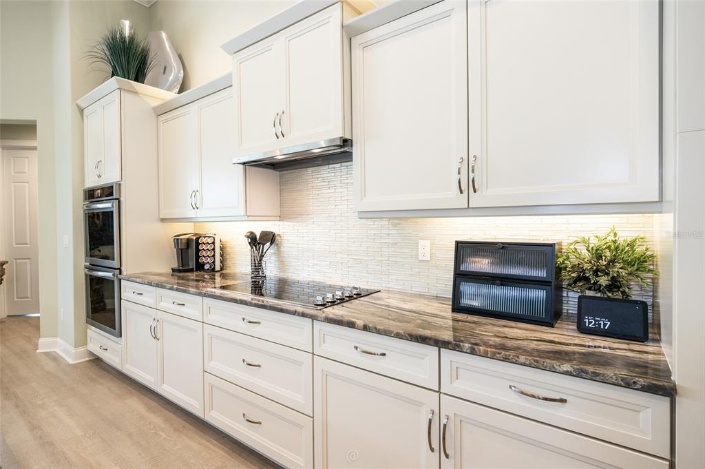 A kitchen features white cabinets, dark stone countertops, a tiled backsplash, and built-in wall ovens — 478 SWEETGUM LANE, PALM COAST, FL