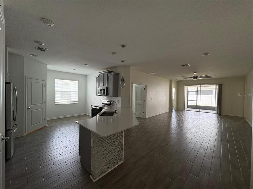 An open-concept kitchen and living area feature gray tile flooring and a stone-accented island — 2710 SLASH WAY, ST CLOUD, FL