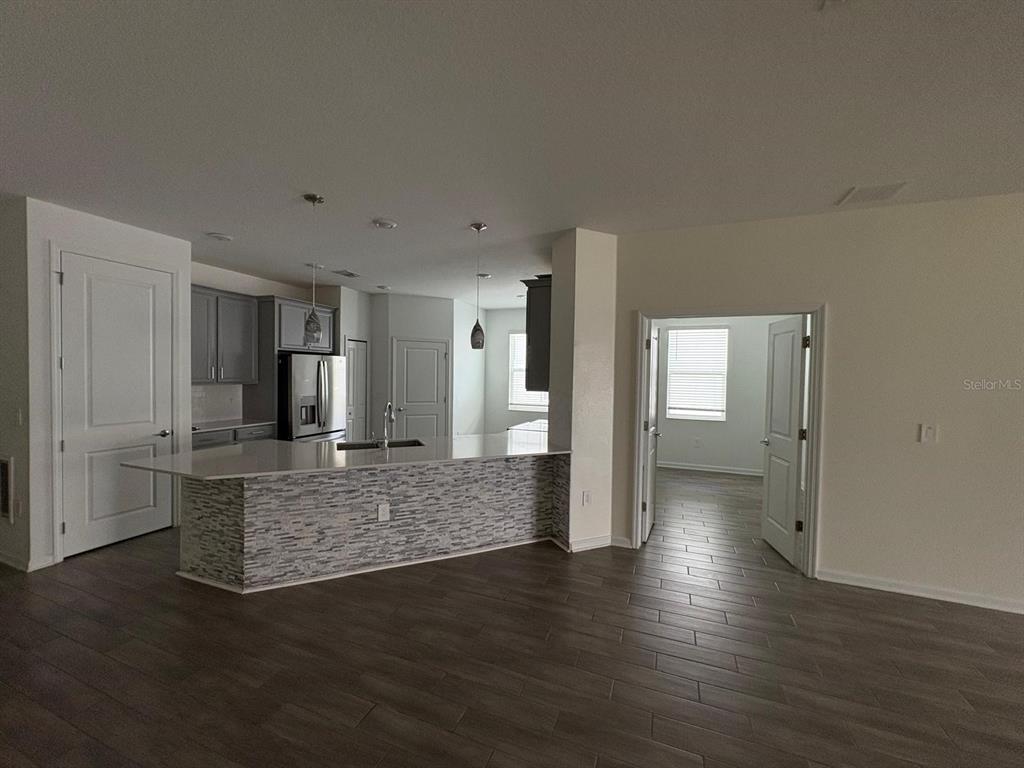 A kitchen with a stone-faced island and gray cabinets opens into a living area — 2710 SLASH WAY, ST CLOUD, FL