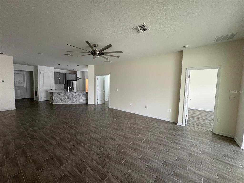 An open-concept living area features wood-look tile flooring, a ceiling fan, and a kitchen island — 2710 SLASH WAY, ST CLOUD, FL