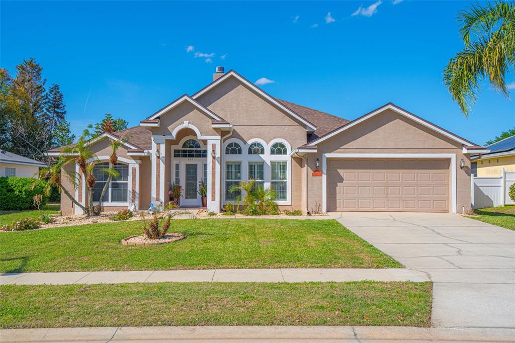 A single-story tan house with a two-car garage and a front-facing arched entryway — 484 KETTERING ROAD, DELTONA, FL