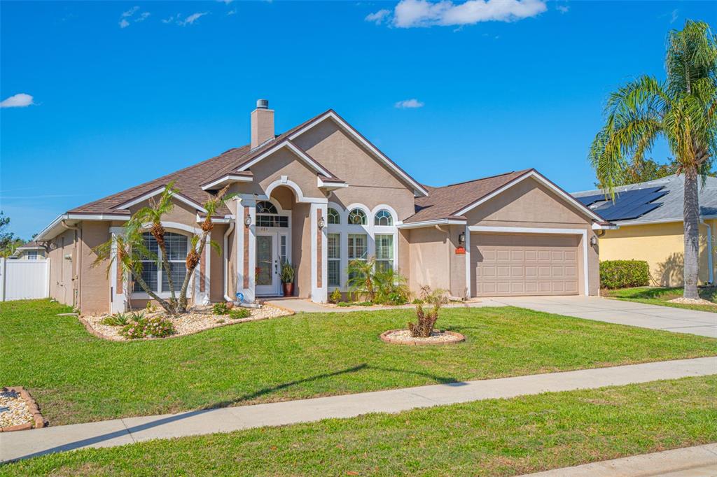 A single-story suburban house with a tan stucco exterior, brown roof, and two-car garage — 484 KETTERING ROAD, DELTONA, FL