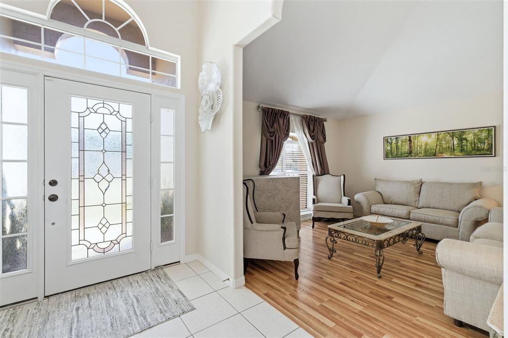 A tiled entryway leads into a living room with hardwood floors and neutral furniture — 484 KETTERING ROAD, DELTONA, FL