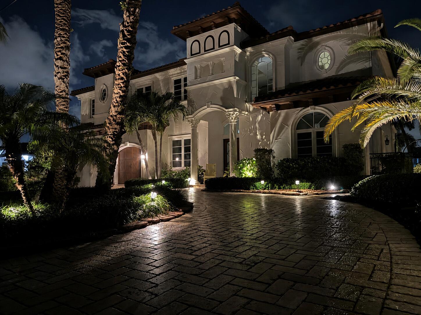 A two-story Mediterranean-style house with a paved driveway and palm trees at night — 4431 NE 24th Avenue, Lighthouse Point FL 33064, LIGHTHOUSE POINT, FL