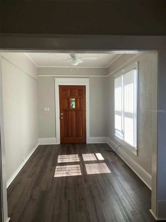 A room with gray walls, dark wood-look flooring, a wooden front door, and white trim — 910 S PARK AVENUE UNIT A, SANFORD, FL