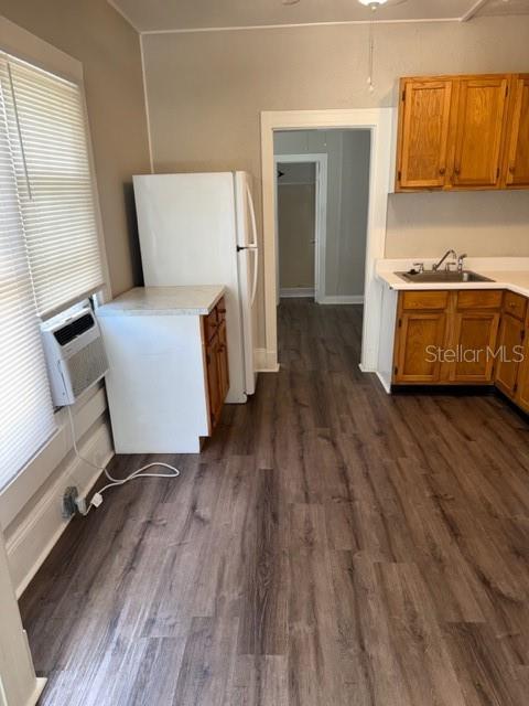 A kitchen features wood-look flooring, light-colored walls, wooden cabinets, and a white refrigerator — 910 S PARK AVENUE UNIT A, SANFORD, FL