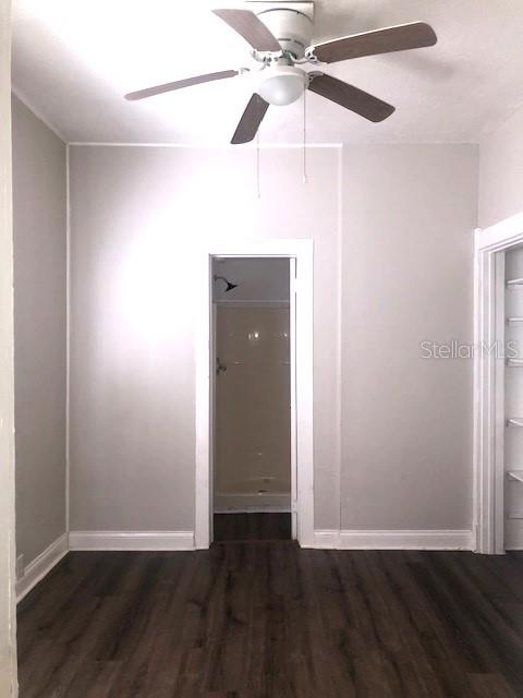 A room with dark wood-look flooring, light gray walls, a ceiling fan, and a doorway — 910 S PARK AVENUE UNIT A, SANFORD, FL