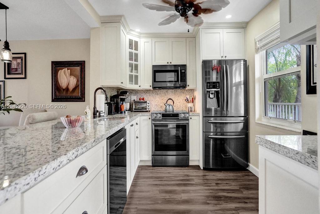 A kitchen features white cabinets, granite countertops, stainless steel appliances, and wood-look flooring — 415 SE 11th Ter # 207, Dania Beach FL 33004, DANIA BEACH, FL